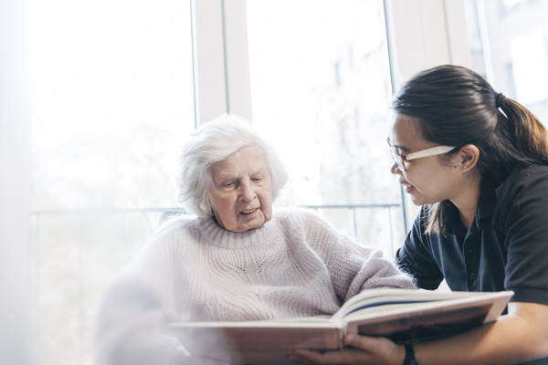 Pflegekraft liest Patientin vor